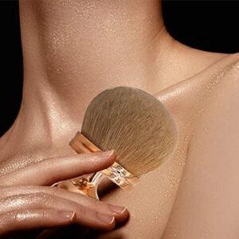 Pinceau de maquillage appliquant de la poudre sur la clavicule d’une personne.