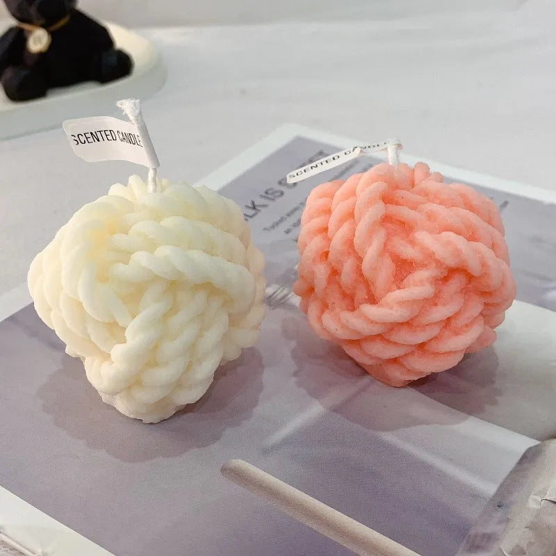 Deux bougies décoratives en forme de cerveau, de couleur blanche et rose corail.