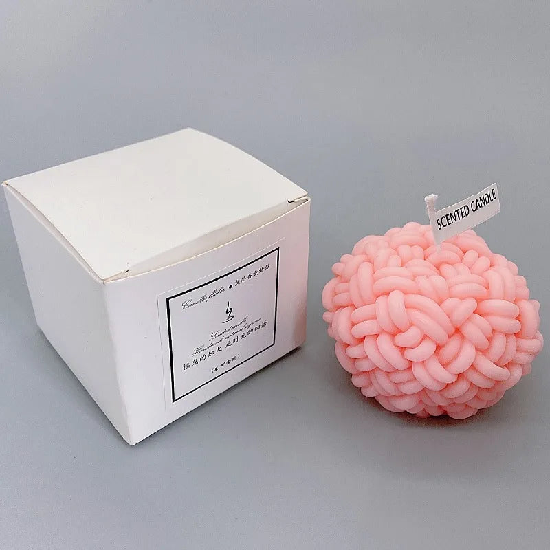 Bougie décorative en forme de cerveau rose à côté de sa boîte d’emballage blanche.