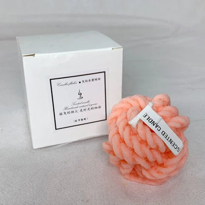 Bougie sphérique rose avec un motif texturé tressé ou tissé.