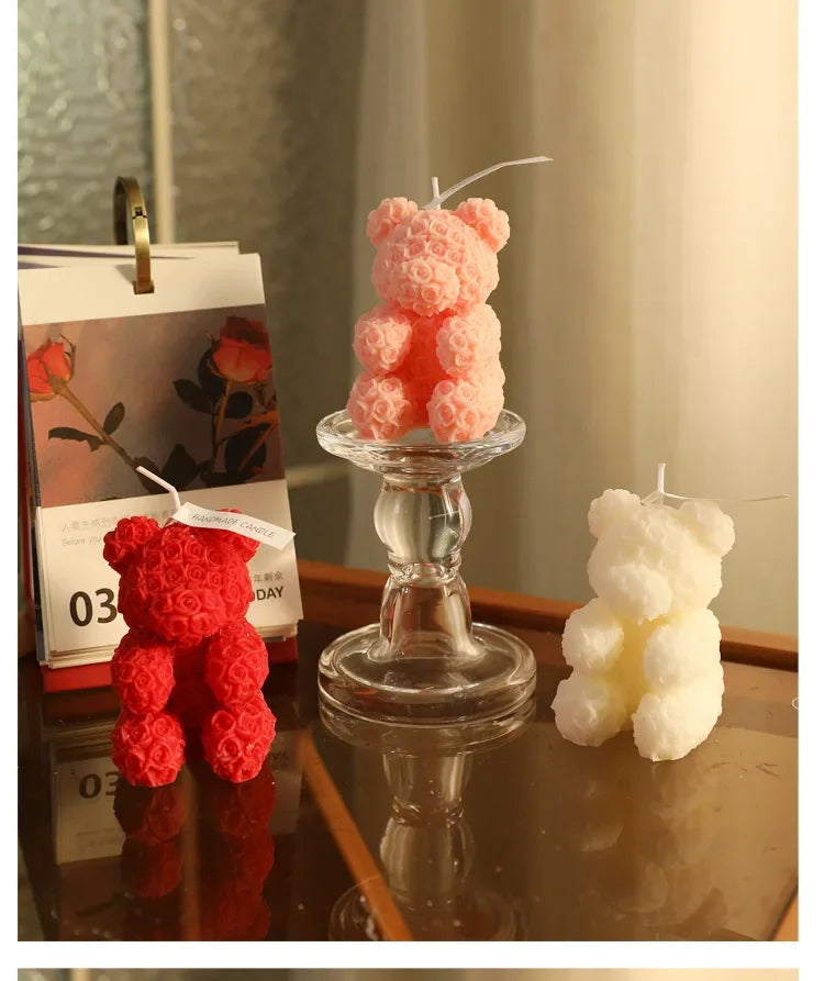 Trois bougies décoratives en forme d’ours en peluche de couleur rouge, rose et blanche.