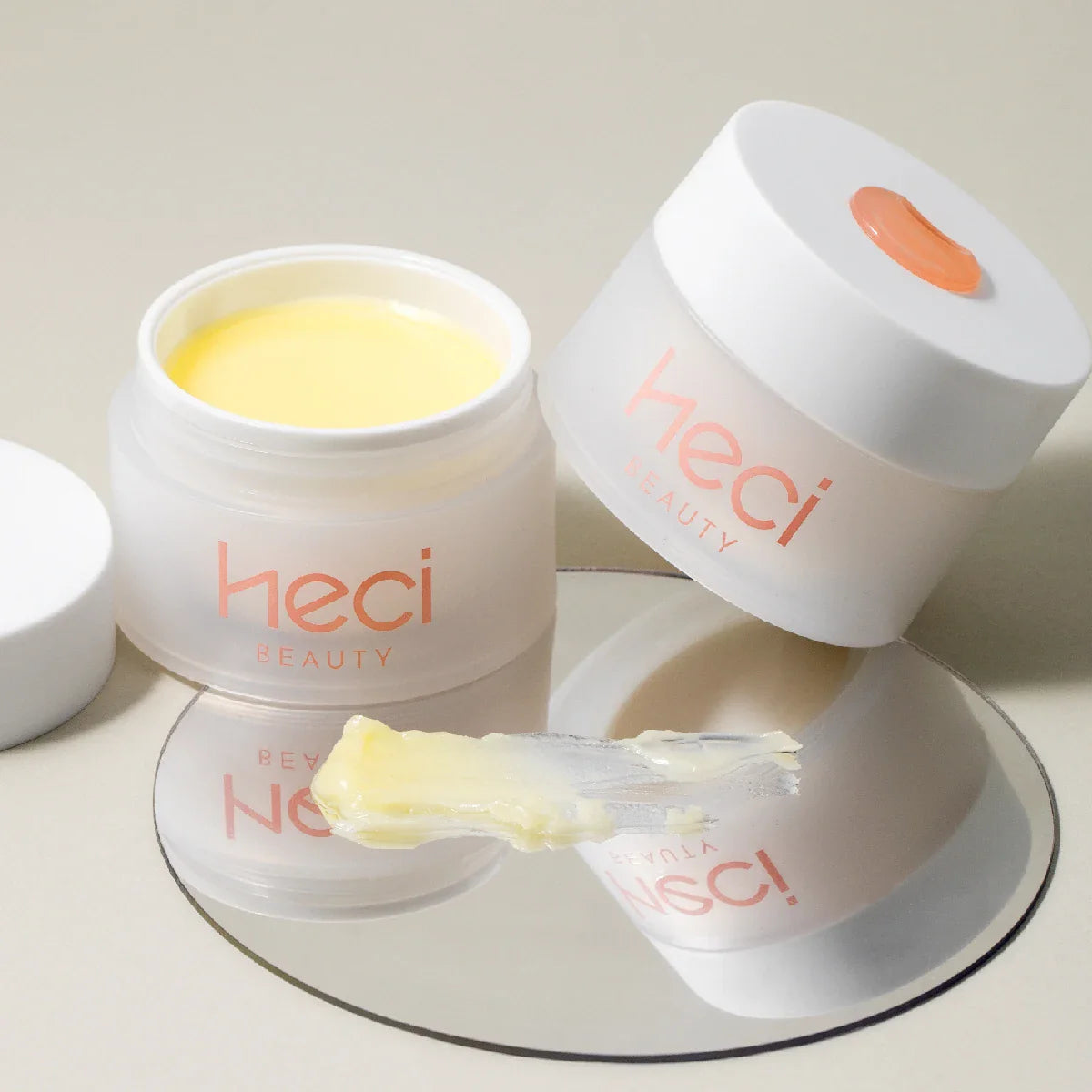 Pots cosmétiques blancs avec marquage ’heci’ contenant de la crème ou du baume jaune.