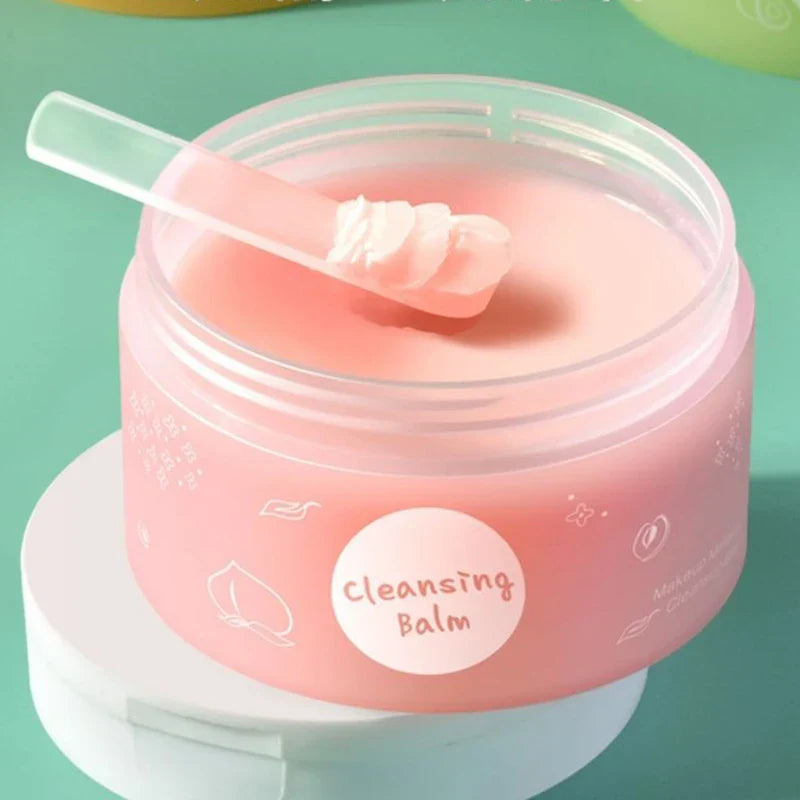 Baume nettoyant rose dans un pot en plastique transparent avec une spatule.