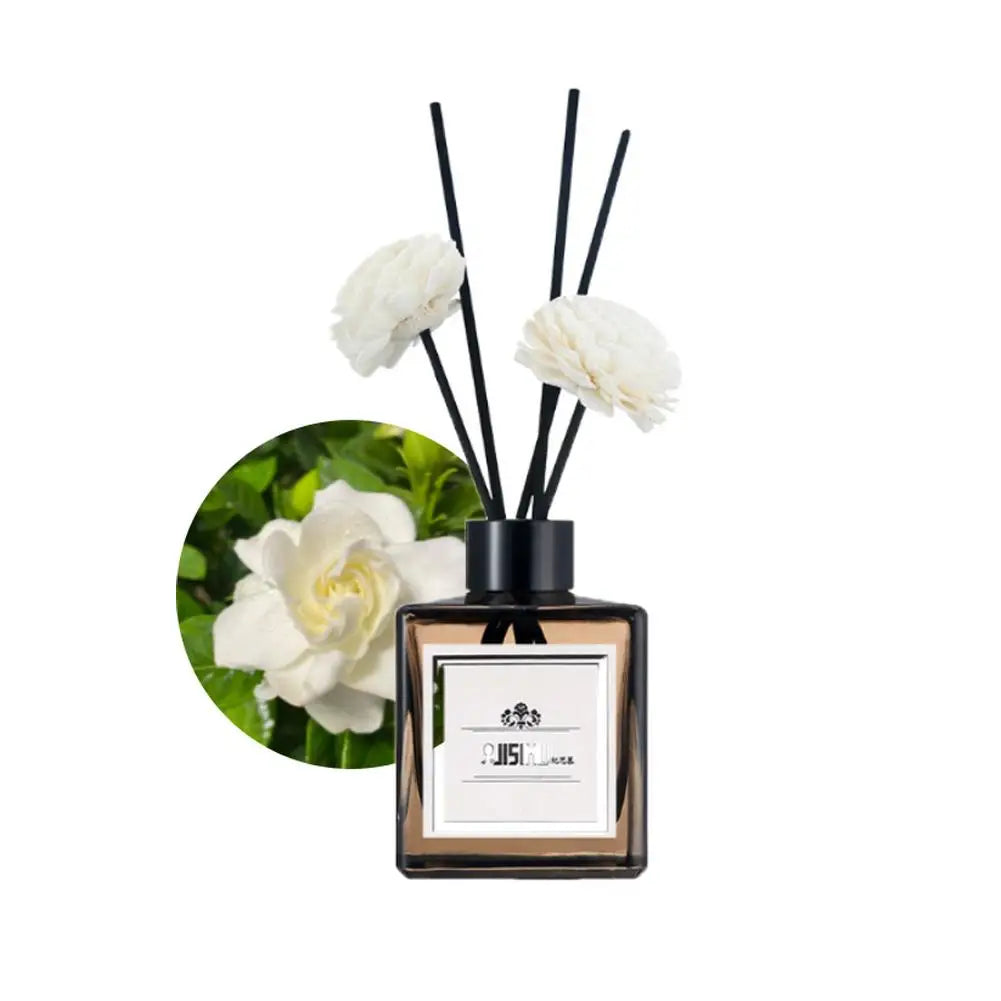 Diffuseur en roseau noir avec des fleurs blanches et un flacon carré en verre contenant de l’huile de parfum.