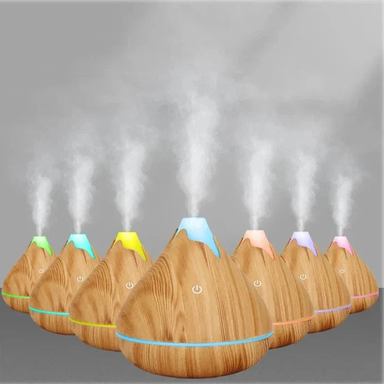 Des diffuseurs d’huiles essentielles en bois avec des lumières LED colorées et de la vapeur s’élevant de leur sommet.