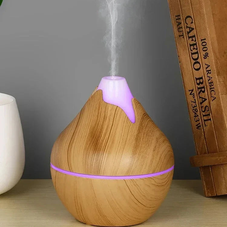 Diffuseur d’huiles essentielles en bois avec éclairage LED violet émettant de la vapeur.