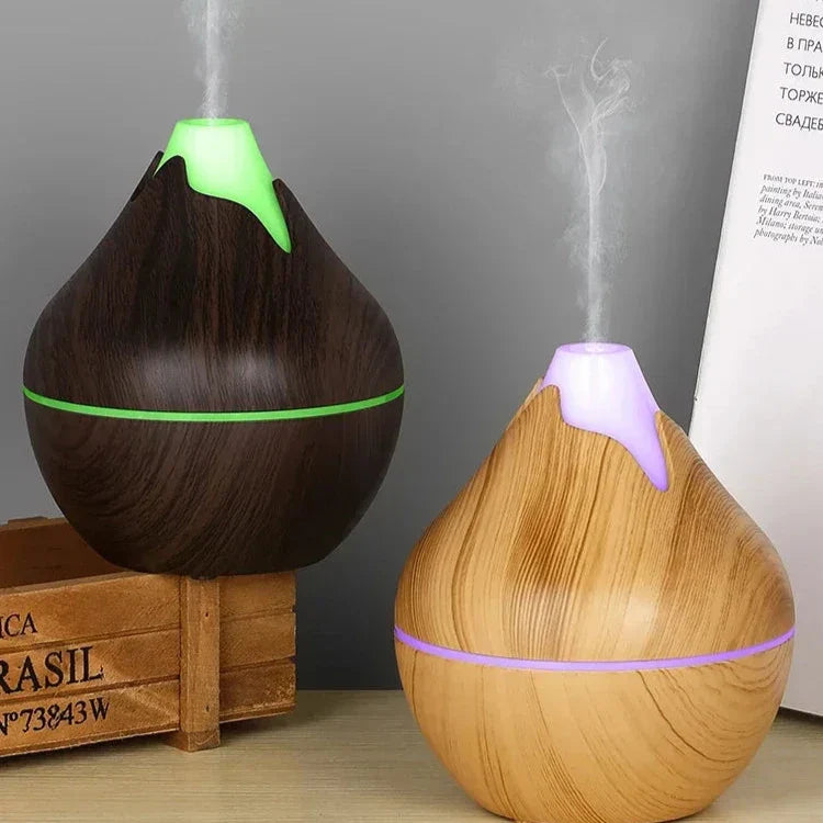 Deux diffuseurs d’huiles essentielles en grain de bois avec des têtes lumineuses émettant de la vapeur.