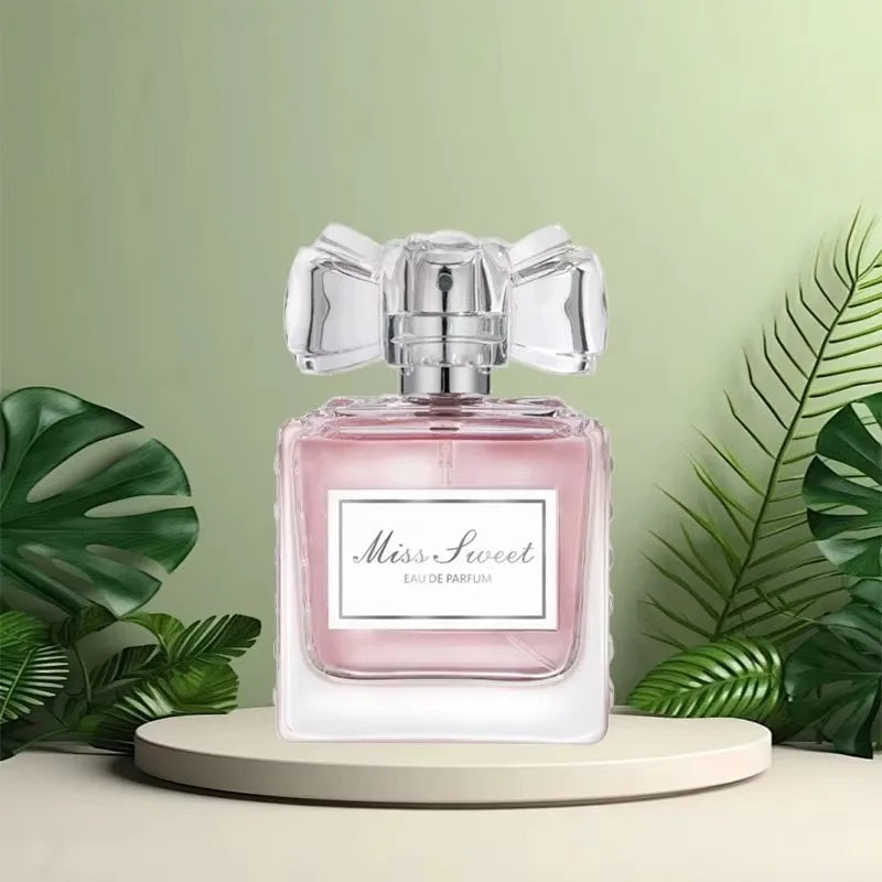 Flacon de parfum rose avec un bouchon argenté en forme de noeud et une étiquette ’Miss Sweet’.