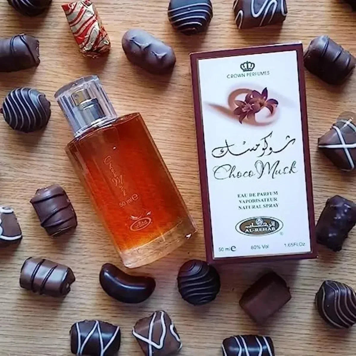 Un flacon de parfum entouré de truffes au chocolat et de sa boîte d’emballage.