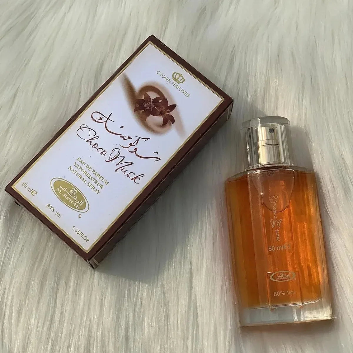 Flacon de parfum et sa boîte d’emballage avec un texte arabe sur une surface blanche.