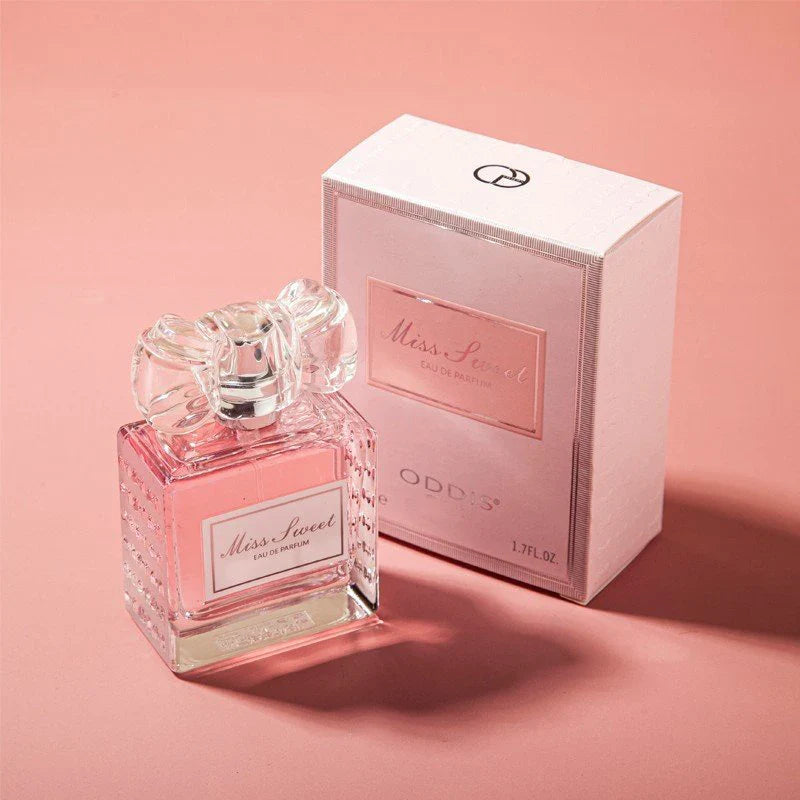 Flacon de parfum rose avec un bouchon en verre décoratif et sa boîte de vente assortie.