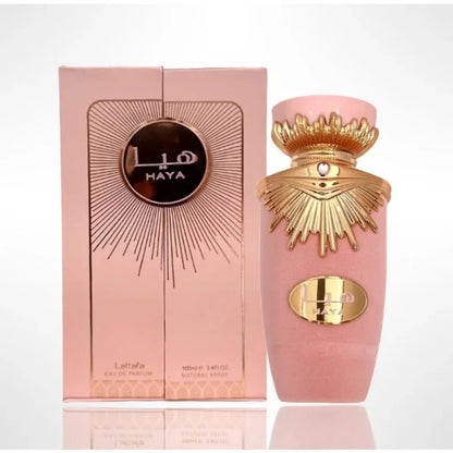 Flacon de parfum rose avec une couronne dorée et un texte en arabe sur l’emballage.