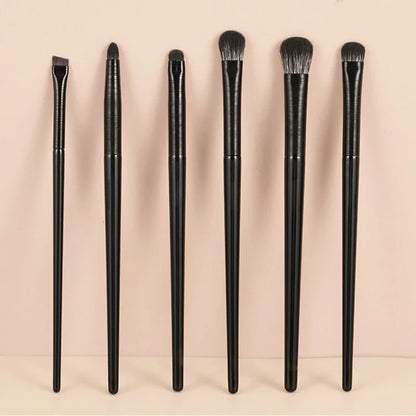 Six pinceaux de maquillage noirs disposés en rangée.