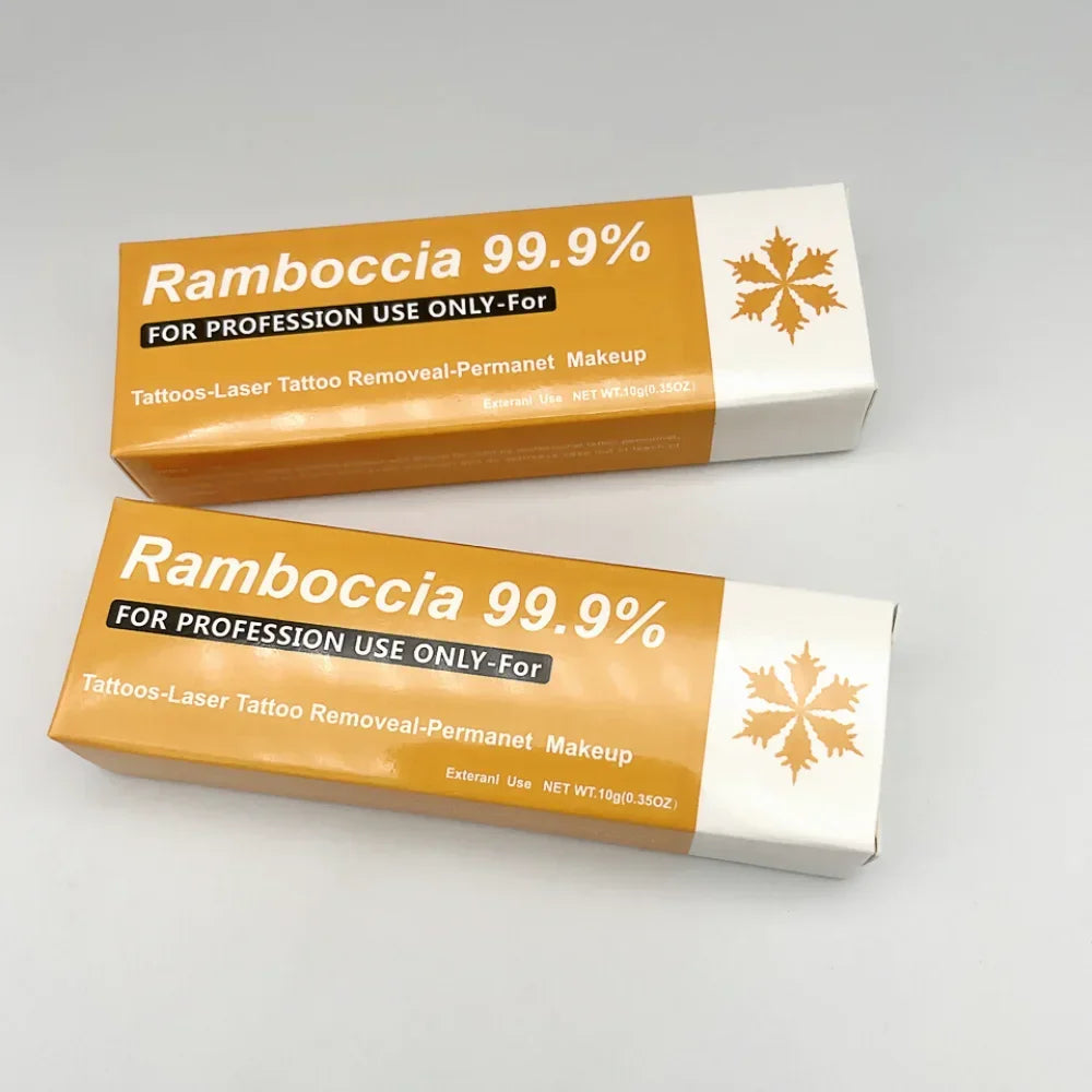 Deux boîtes orange et blanche de produit Ramboccia 99,9% pour l’élimination professionnelle des tatouages.