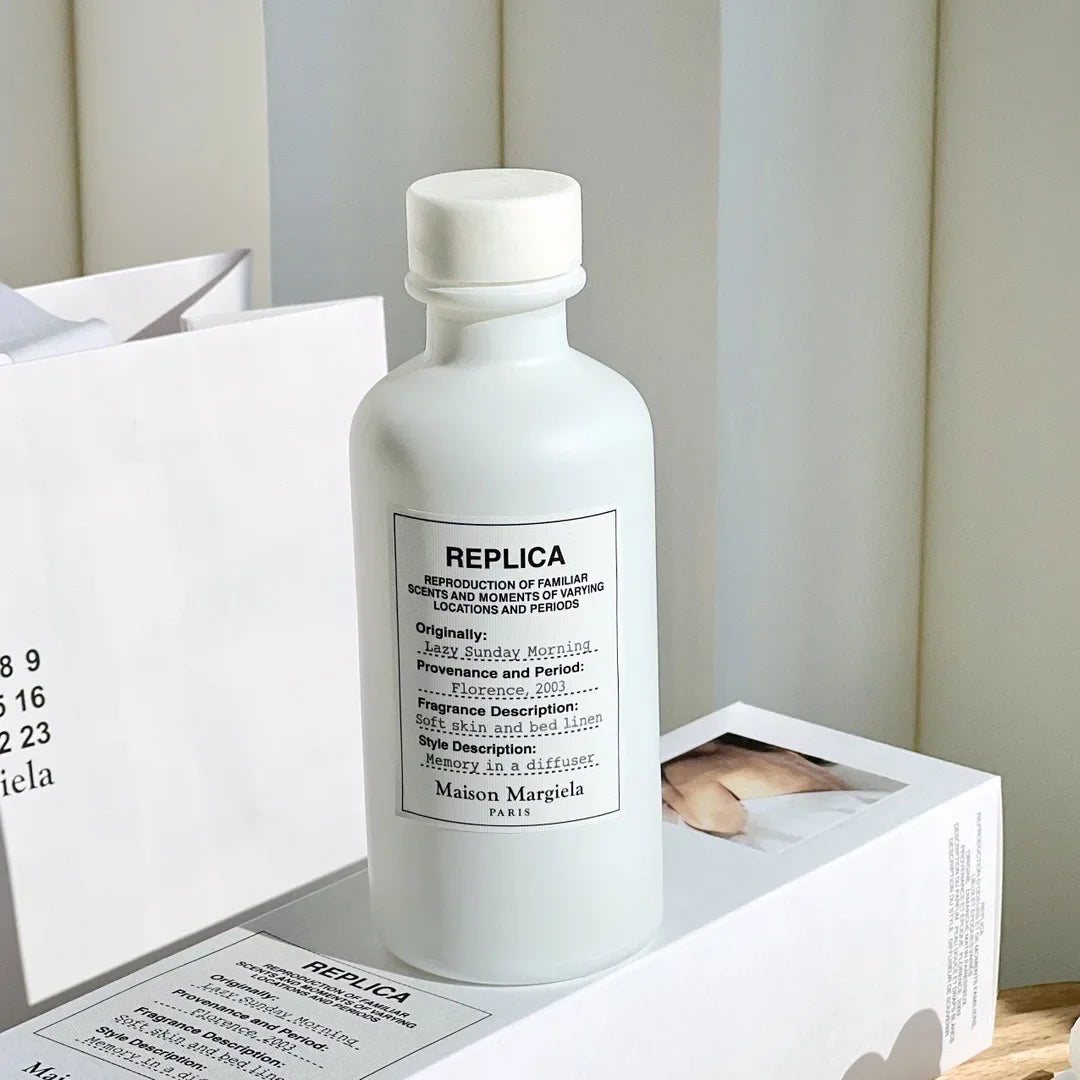 Flacon en verre givré blanc avec une étiquette ’Replica’ de Maison Margiela.