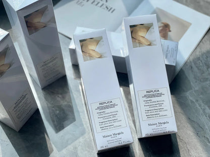 Boîtes de parfum Maison Margiela Replica blanches disposées en rangée.