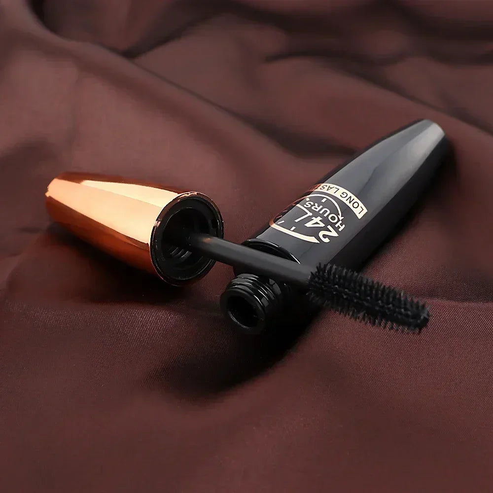 Tube de mascara noir avec baguette ouvert sur le tissu.