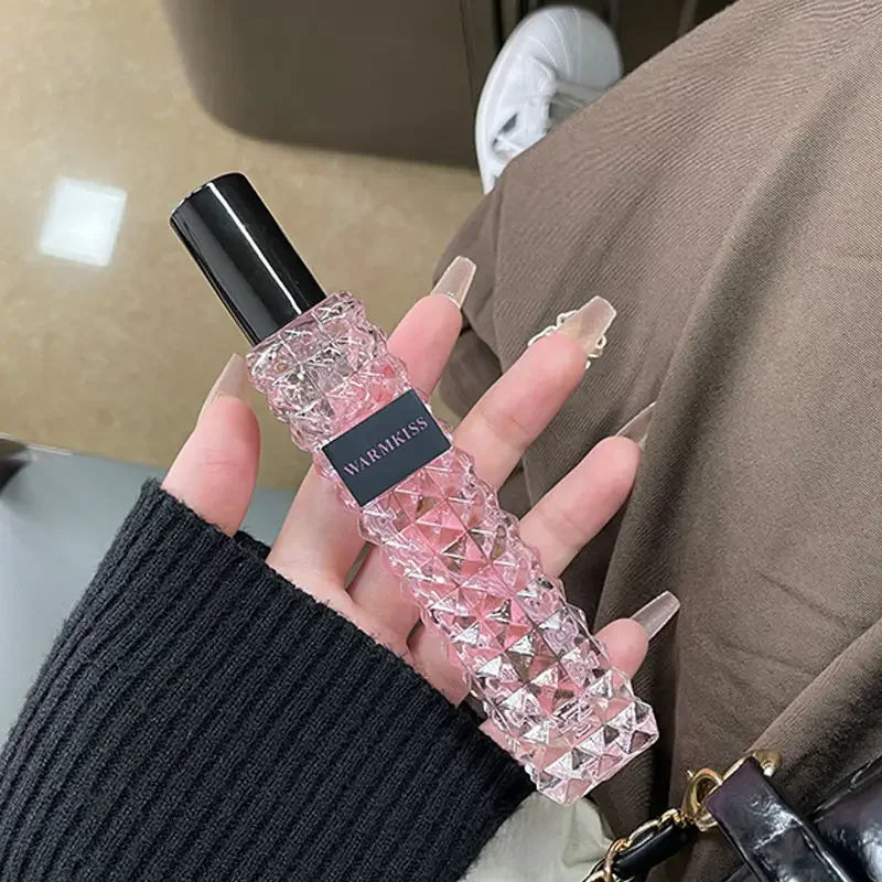 Flacon de parfum rose texturé en cristal avec un bouchon noir.